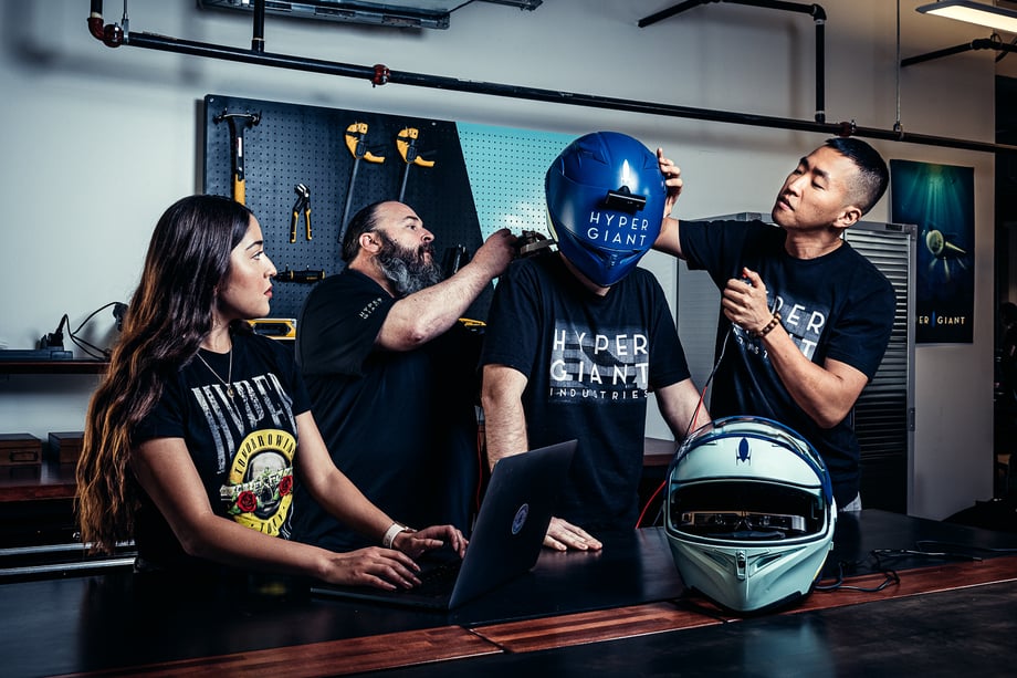 John Davidson snaps a photo of members of Hypergiant's team help with a specialized helmet