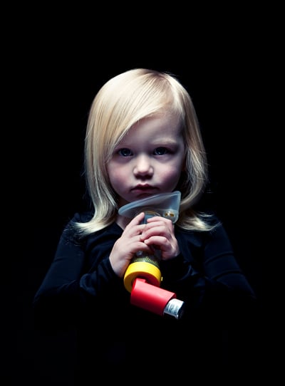 Young child holding an inhaler close to her face shot by Los Angeles-based portrait photographer Kyle Monk for Cystic Fibrosis Foundation 