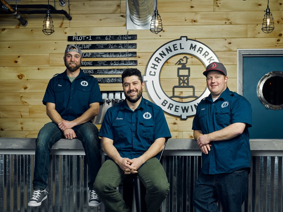 Doug Levy's photo of Tim, Justin, and Jake in front of their brewing company logo