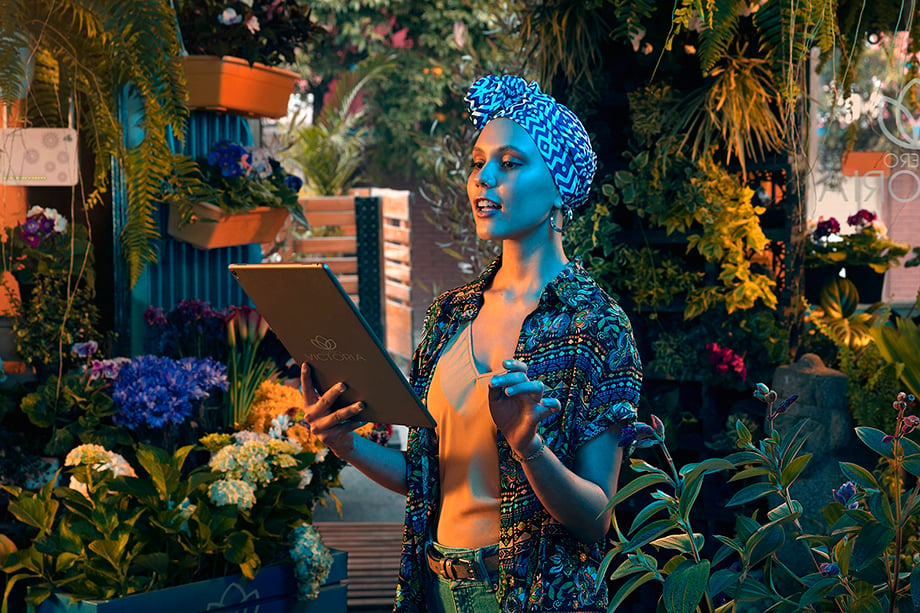 Jorge Oviedo photographs a woman in a headscarf surrounded by plant life as she scrolls on her screen for ETB