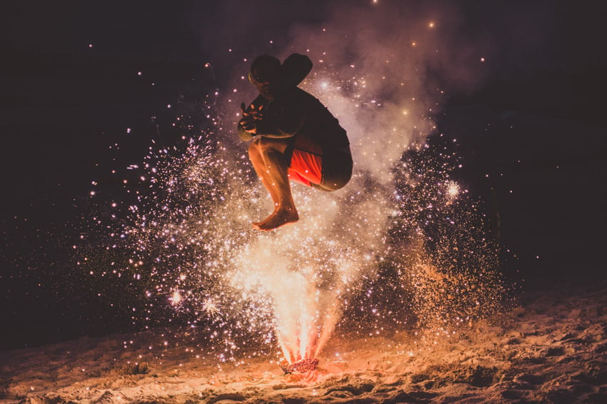 Photograph by Josh Letchworth of a man jumping in front of fireworks on a beach.