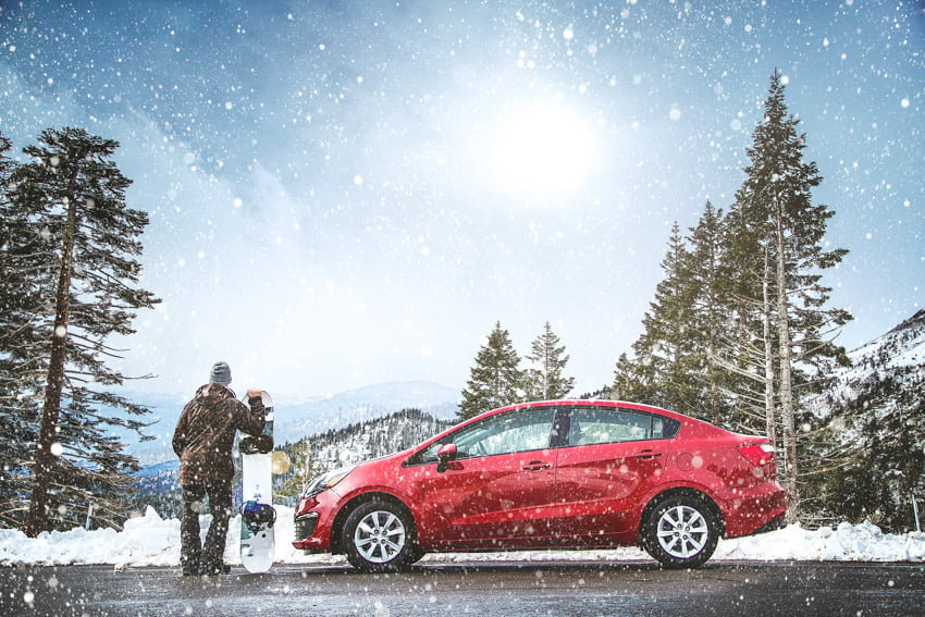 Will Strawser photographs a bright red car and snowboarder amid a snowy mountainside.