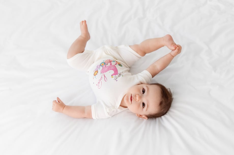 Photo of a baby in Olivia Yves clothing on a bed. 