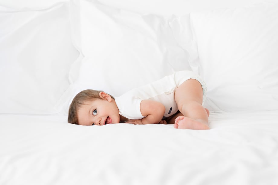 Photograph of a baby in Olivia Yves onesie on a bed taken by Lisa Tichané