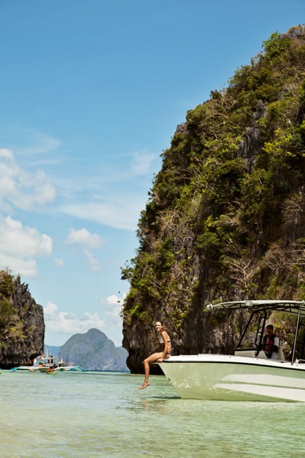 Wide shot of a woman on a boat by a cliff photographed by Francisco Guerrero