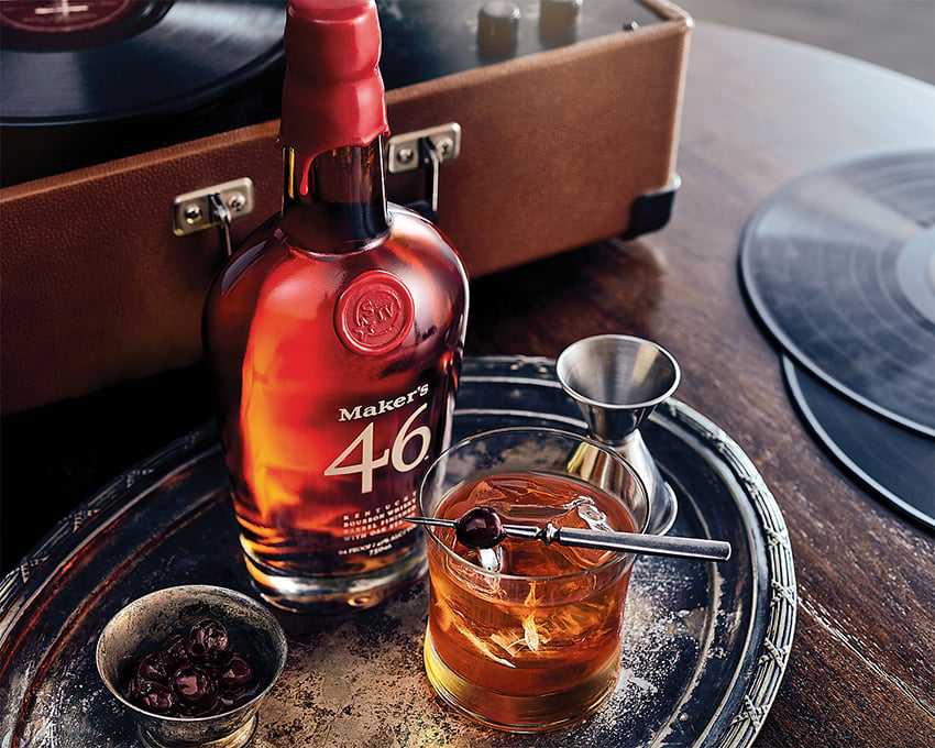 A glass of Maker's Mark sitting by the bottle next to a vintage record player