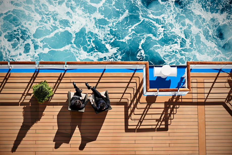 An overhead shot captures guests sitting on the deck, holding hands, looking out over the water