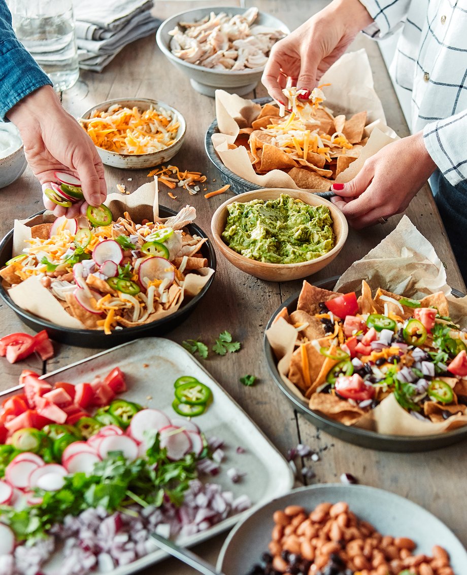 Colin Price gets a close up of a nacho bar with toppings: guac, cheese, and assorted vegetables