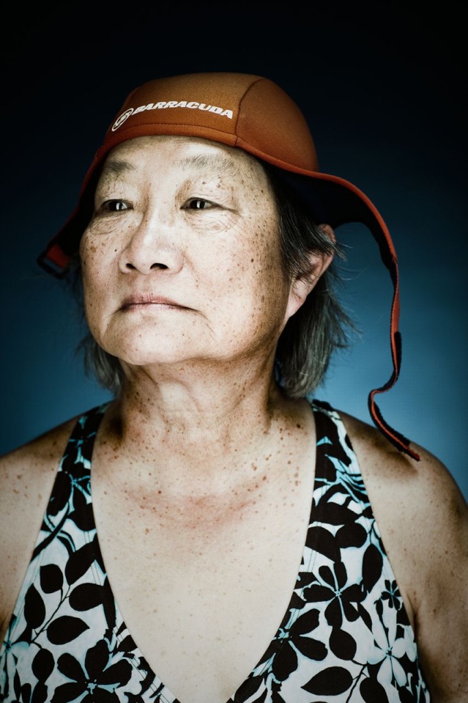 Portrait of an older female swimmer in a floral swimsuit and orange cap photographed by Vance Jacobs.