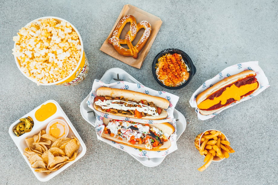 Overhead photo by Krystal Thompson of stadium food: popcorn, soft pretzel, fries, dogs, and nachos.