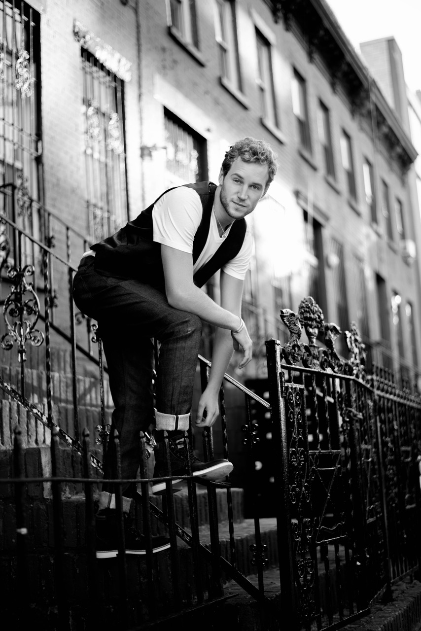 Kate Holliday's model, Ryan, is shown standing on an iron gate next to an elaborate railing in front of a brownstone