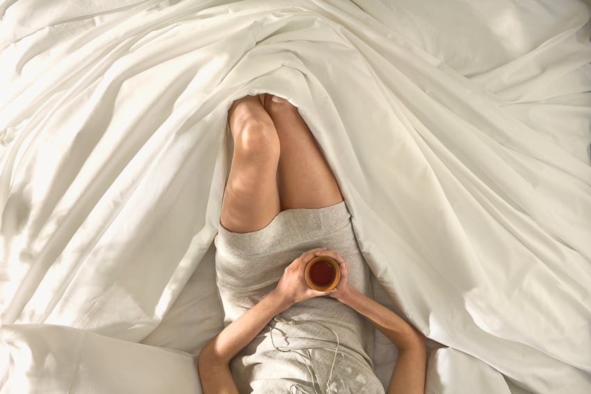 Photograph a model laying in Saatva bedding and drinking a cup of tea for Saatva Dreams by Buff Strickland.