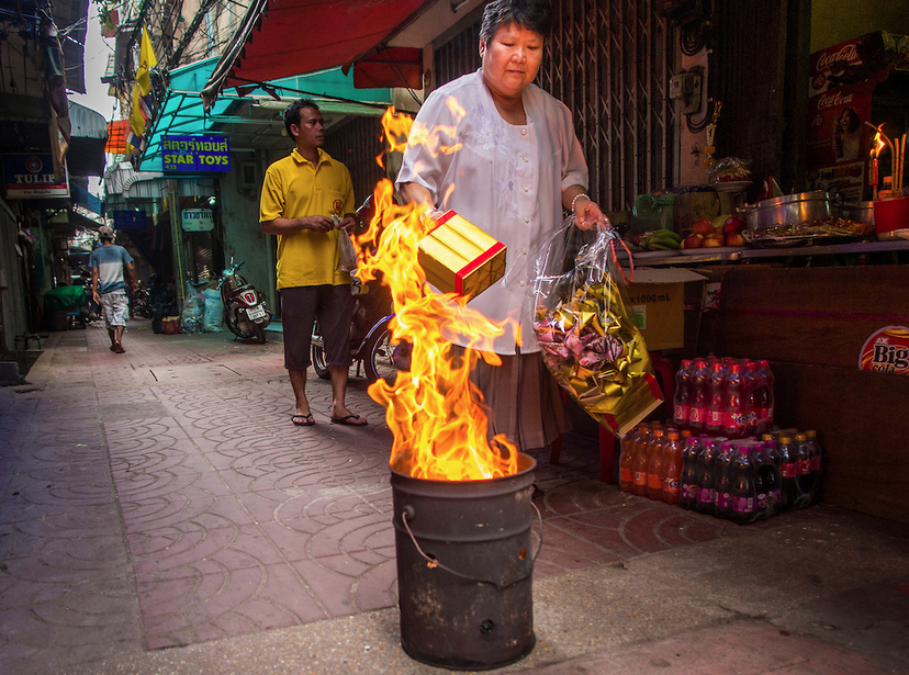 A woman burns joss paper and hell money photographed by Jack Kurtz