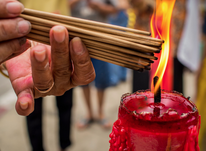 A person lights candles before praying at Pek Leng Keng Mangkorn Khiew Shrine photographed by Jack Kurtz