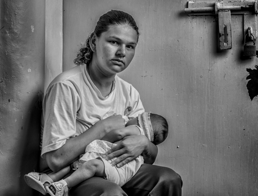 Woman breast-feeding in prison, photograph by Milcho Pipin
