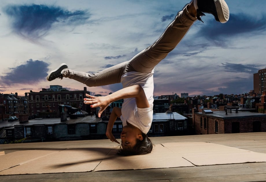 A break dancing woman does a handstand on a Boston roof top, photo by Josh Andrus