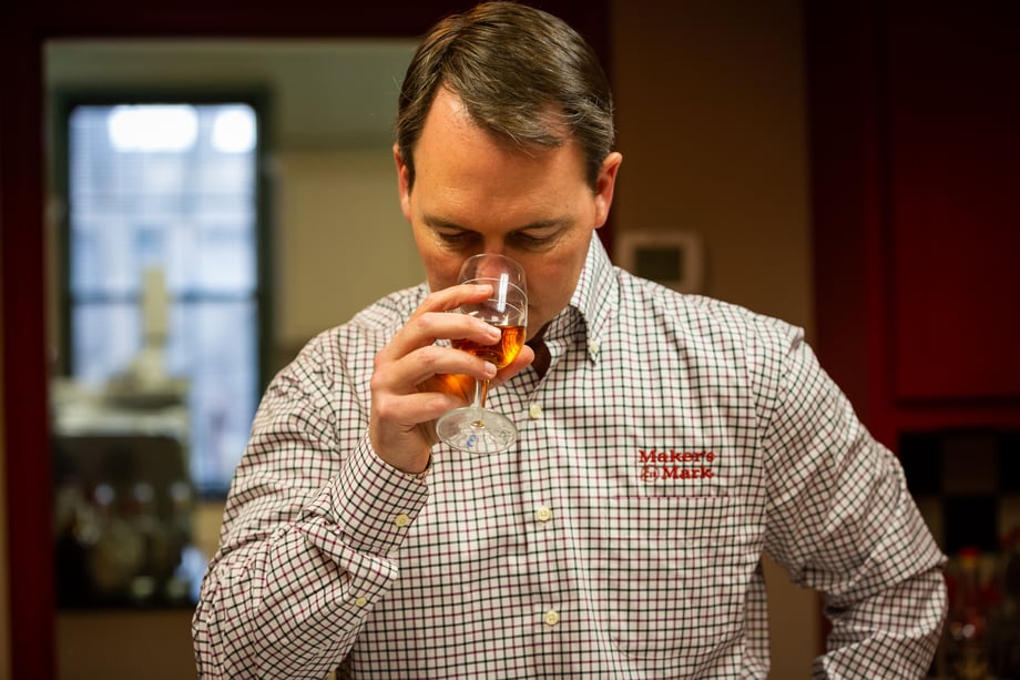 A man in a Maker's Mark shirt tastes bourbon from a snifter in this photo by Matthew Allen