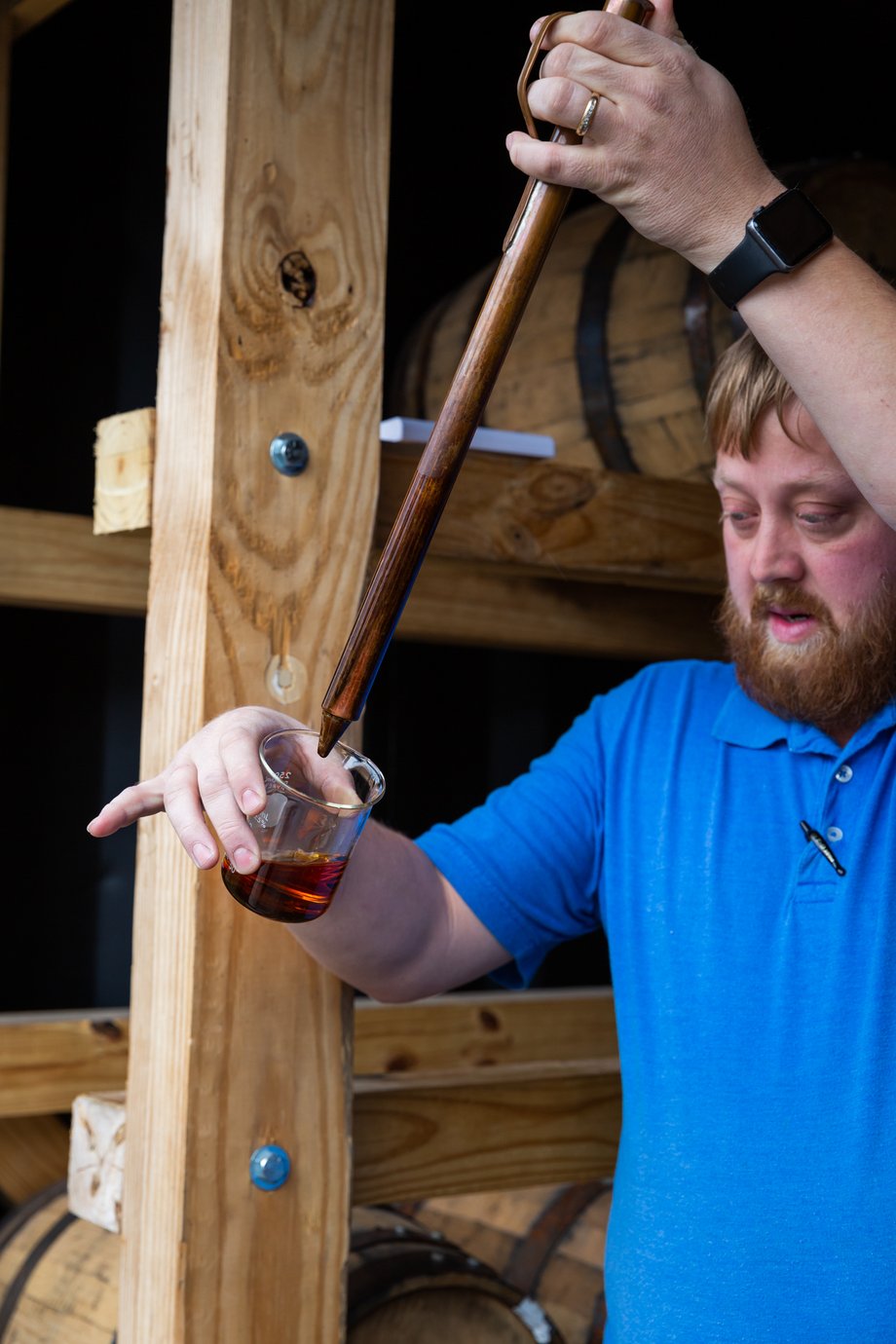 Matthew Allen snaps a photo of a bourbon maker testing a beaker of bourbon with a specialized tool
