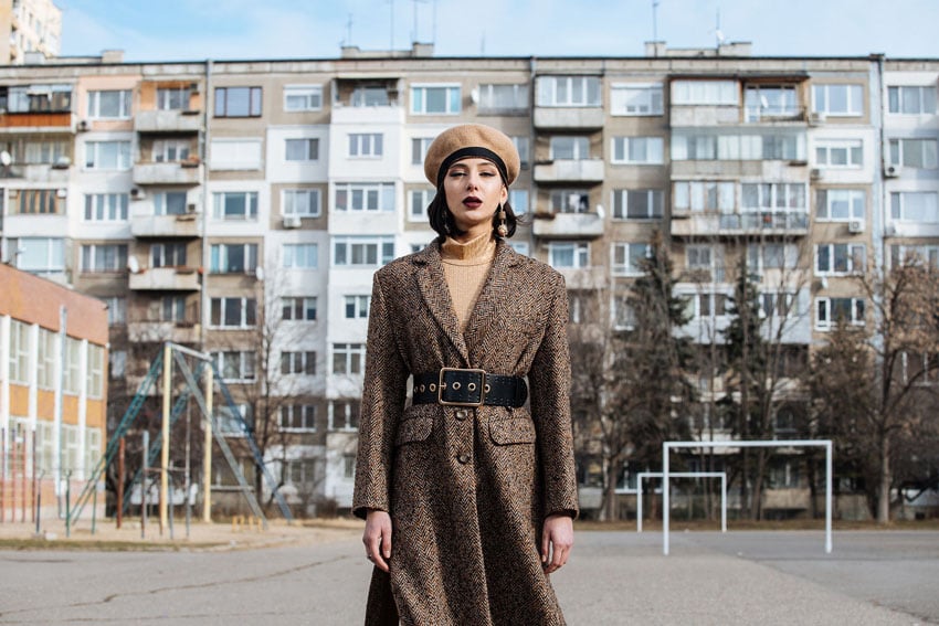 Tina Boyadjieva's Bulgarian Fashion Shoot shows a model in a long belted coat with a school in the back