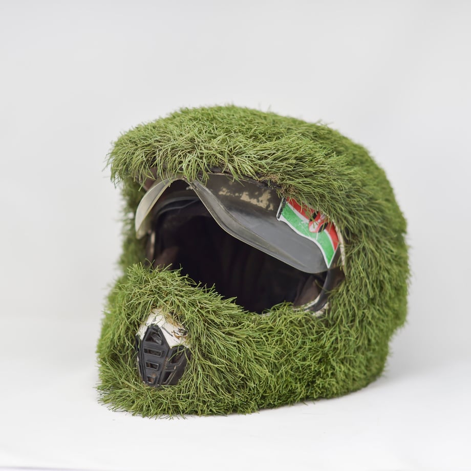 This Boda Boda helmet is completely covered in green grass except for the visor and breathing vent