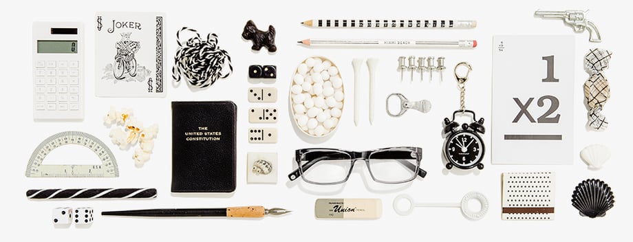 Tearsheet featuring clear glasses with a black tint, surrounded by other similarly-colored objects, shot by New York-based still life photographer Greg Vore for Warby Parker