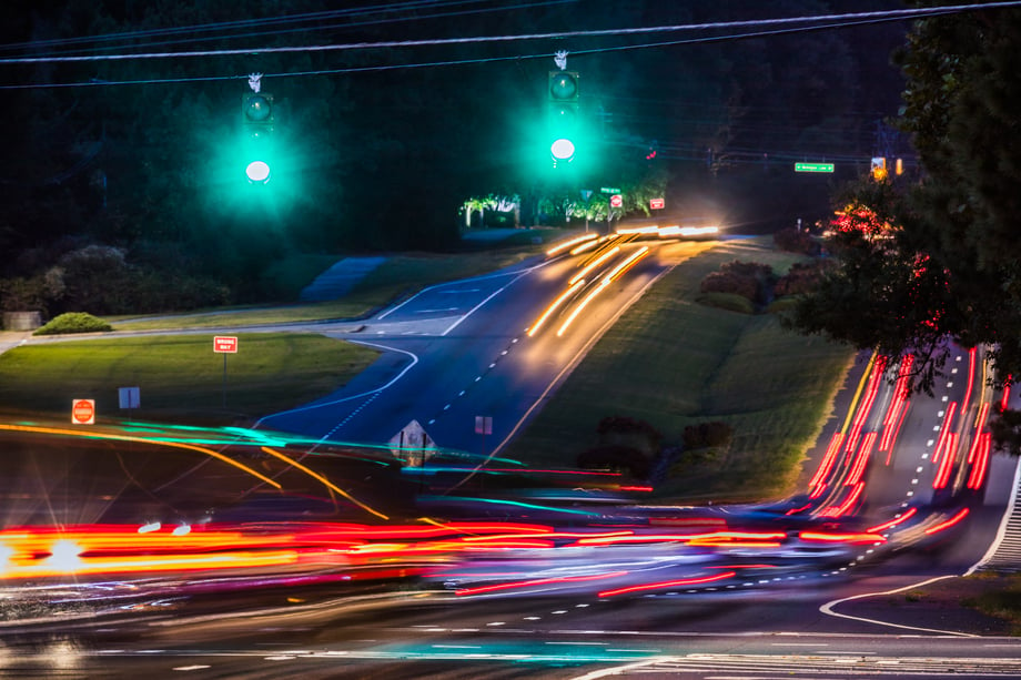 Photo by Joe Boris of cars speeding at nighttime making for an effect of lights stretching.