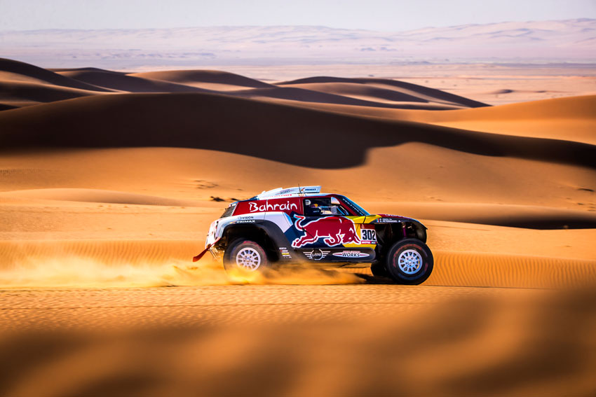 Photo of a Dakar Rally Red Bull vehicle speeding through the desert.