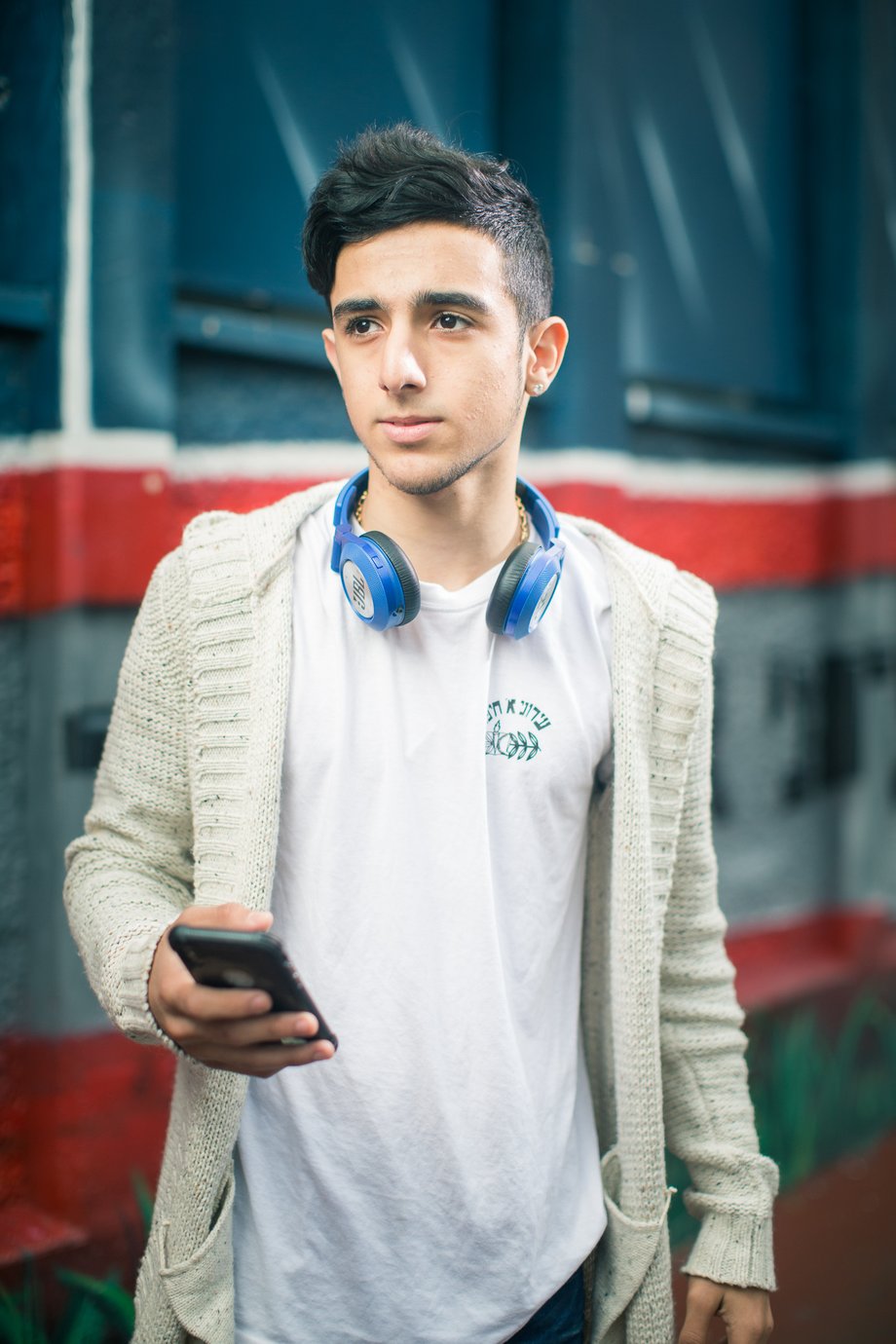 Ronen Goldman's portrait of a student holding a cell phone and wearing a headset around his neck