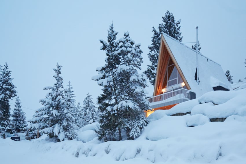 Photo of an A-frame cabin on a snowy peak.