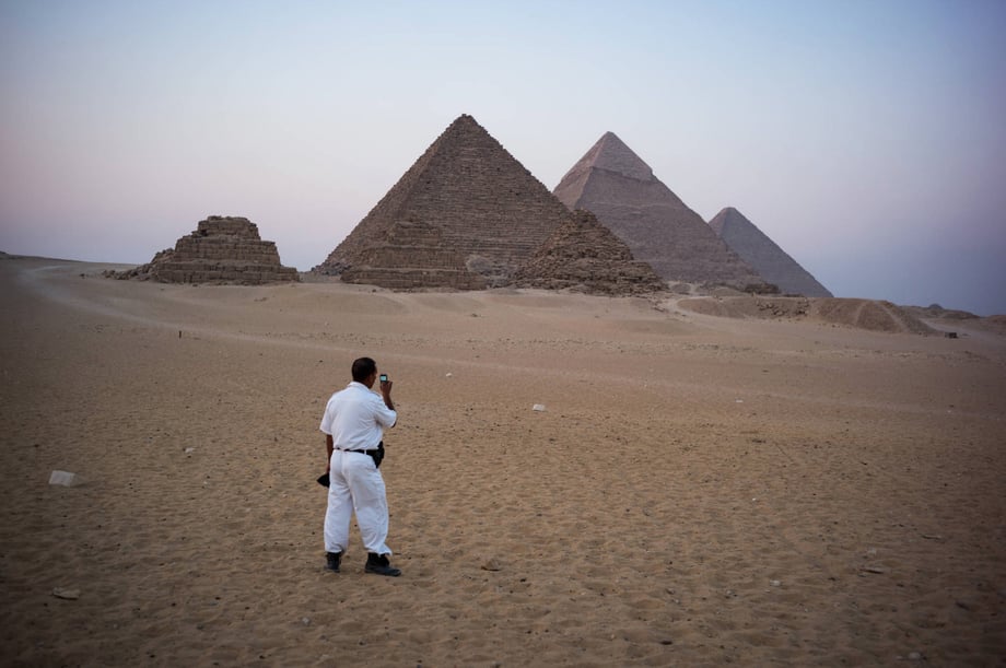 a man takes a picture of the pyramids on his cell phone
