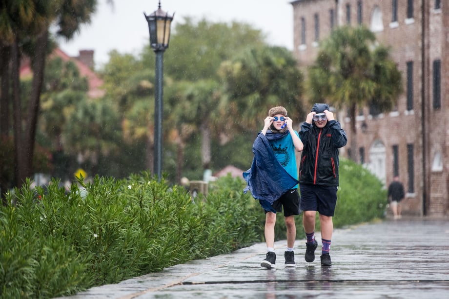 Sean Rayford snaps a photo of two local boys walking on a sidewalk in Charleston wearing rain gear and goggles