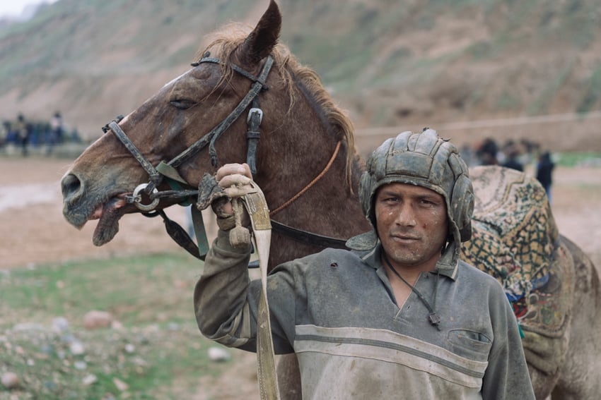 Buzkashi rider with traditional head protection by Marc Ressang