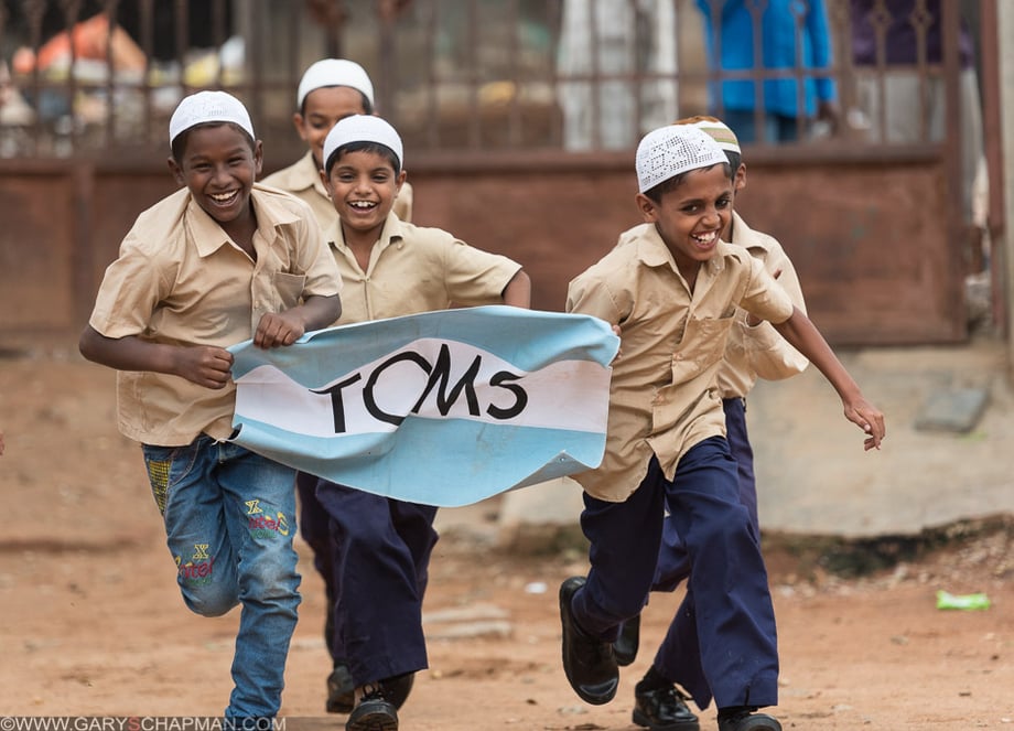 A group of happy children run with a toms flag in their hands, image by Gary Chapman