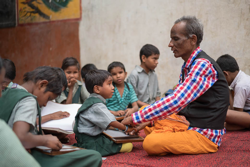 Vishnu, a blind teacher, helping blind students learn braille at his school, photo by Gary Chapman