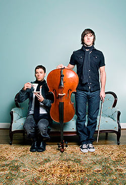 A photo of members of the band Lynden holding an upside down cello by Josh Cole.