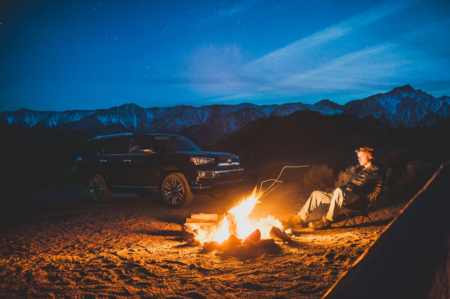 Toyota 4Runner and a camper pictured next to a cozy fire in a mountainous region, photo by Mark Skovorodko