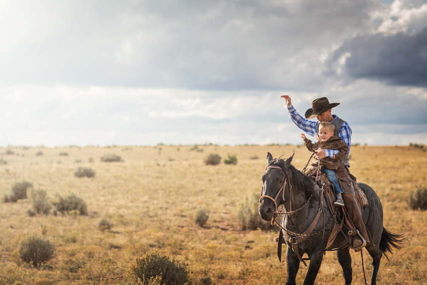 Photograph by Michael Kunde of a cowboy and child riding a horse in Utah