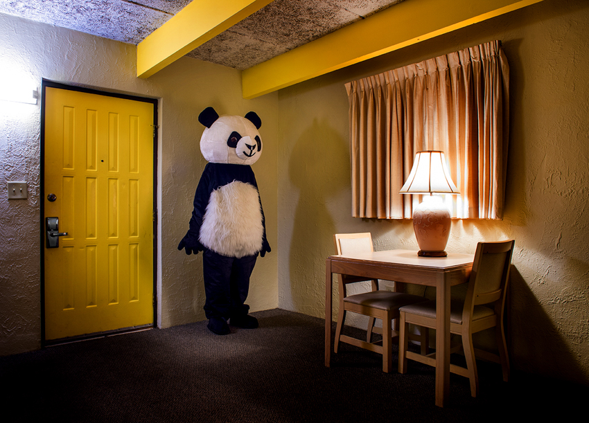 A person in a panda suit stands near a hotel room door. Image by Bryan Regan.