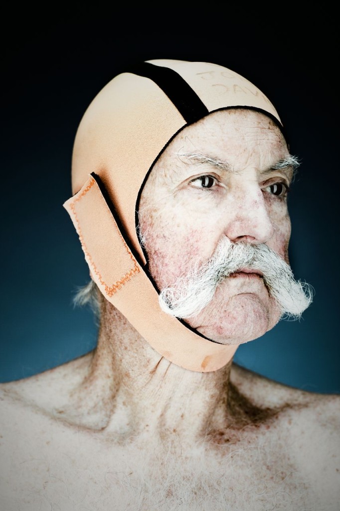 Portrait of a mustachioed swimmer with an orange and black swim cap photographed by Vance Jacobs.