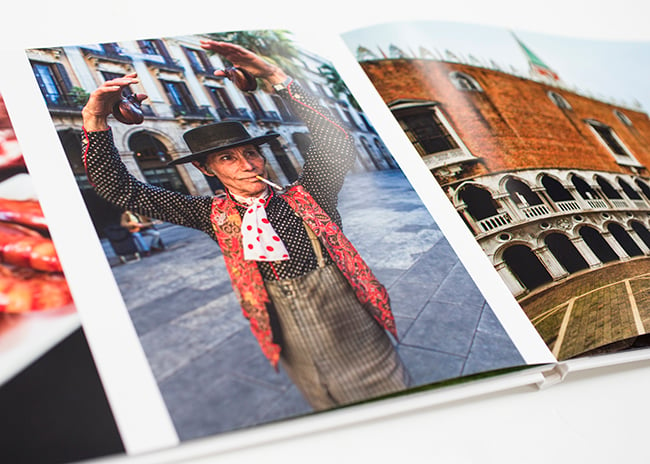 A print portfolio opened to a page of a person with their arms above their head; travel photography