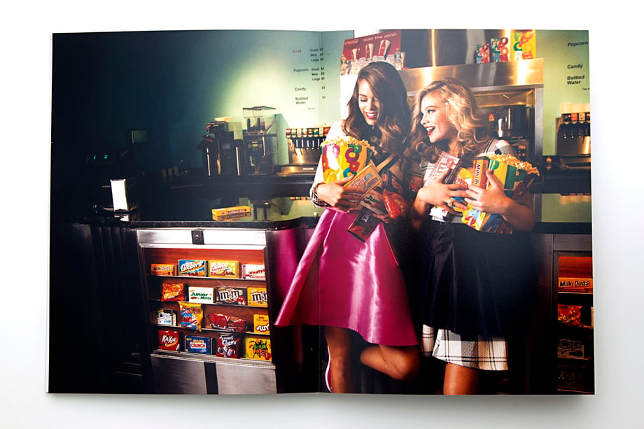 Photo by Sean Scheidt of two girls holding a bunch of snacks at the concession stand a movie theater.