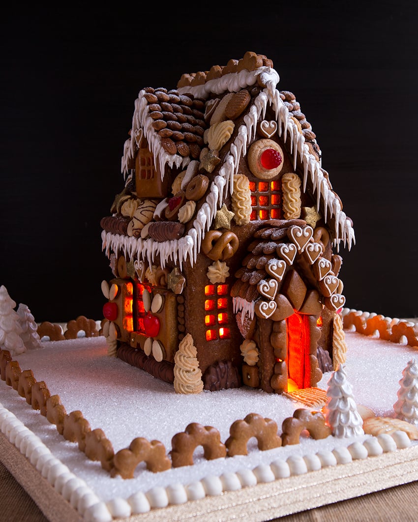 Nighttime photo of a gingerbread house for book A Year of Gingerbread Houses by Kristine Samuell.