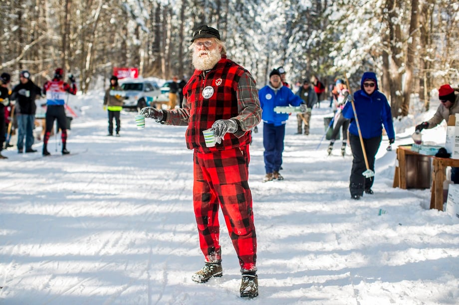 A man in flannel handing out cups to the skiers, photograph by Narayan Mahon