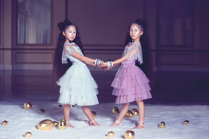 Two young girls in tutus among a field of golden eggs, photograph by Megan Dendinger