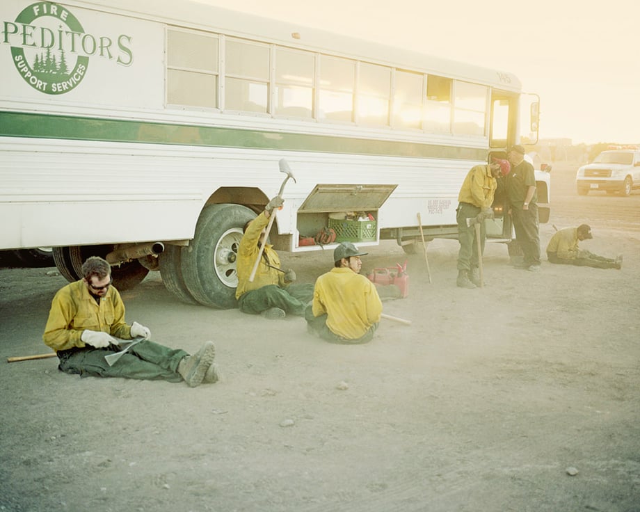 Workers from Fire Support Services sitting on the ground by their bus, with shovels shot by Phoenix-based photojournalist Jesse Rieser