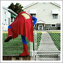 A child in a superman costume climbing over a fence by photographer Scott Ferguson