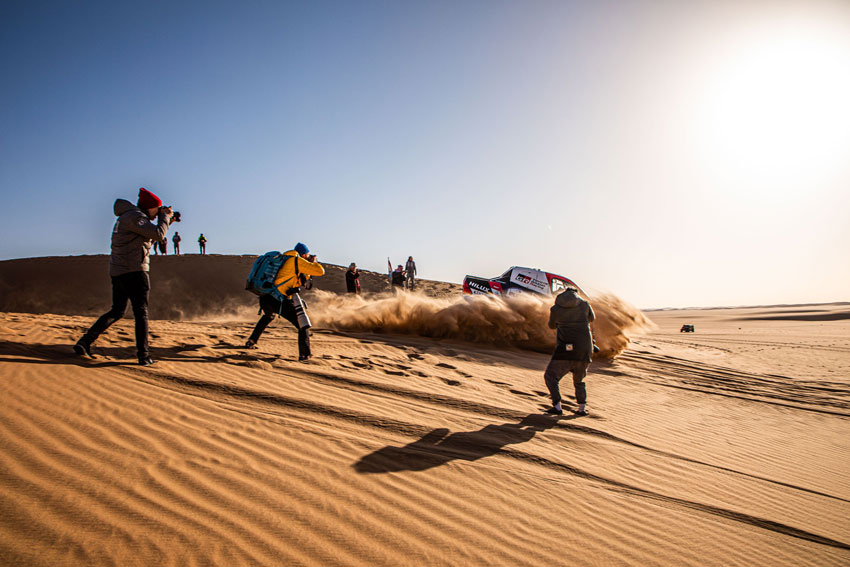 Dakar Rally BTS shot of photographers capturing a fast moving vehicle.
