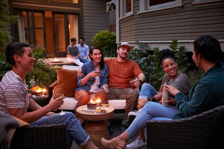 Friends sit in backyard patio surrounded by Nunya bonfire candle shot by John Valls