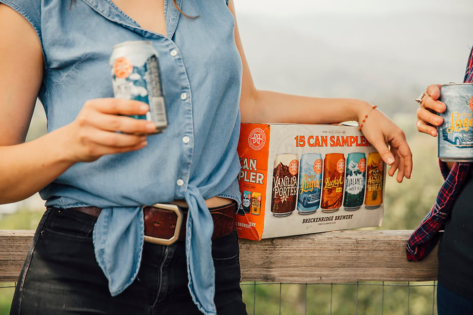Talent leaning against rustic fence with Breckenridge Brewery 15 can sampler pack shot by Jayme Burrows