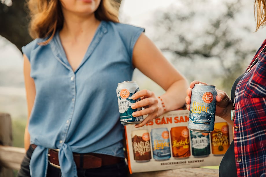 Talent leaning against rustic fence with Breckenridge Brewery 15 can sampler pack shot by Jayme Burrows